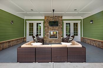 A patio with a wicker sofa and a stone fireplace at Foxwood Apartments, Raleigh-Durham, North Carolina